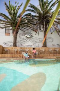 埃斯特角城Selina Punta Del Este的两人坐在棕榈树游泳池旁