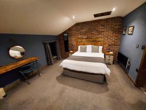 WinewallTrawden Arms Community Owned Pub的一间卧室设有一张大床和砖墙