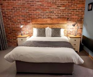 WinewallTrawden Arms Community Owned Pub的一间卧室设有一张带砖墙的大床