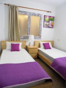 阿尔库迪亚港Tranquilo apartamento con vistas al mar.的紫色床单的客房内的两张床