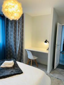 洛里昂Superbe T3 proche de l'hypercentre de Lorient avec terrasse的一间卧室配有一张床、一张书桌和一个吊灯。