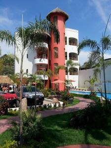 萨尤利塔Hotel y Suites Los Encantos的前面有一辆汽车停在红色的建筑