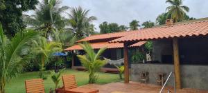 雅帕拉廷加Recanto Ubuntu的房屋设有一座带椅子和棕榈树的庭院