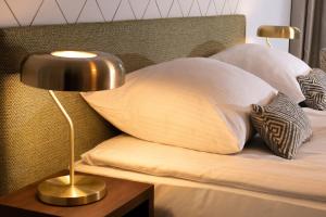 克拉科夫Xerion Hotel的一张带两个枕头的床和一张桌子上的台灯