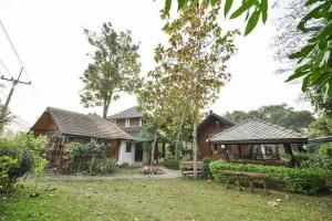 Ban Cham Khaจำค่า ชาเลท์ บ้านพักสวนเกษตร (Jumka Chalet - Home and Farm Stay)的前面有长凳的房子