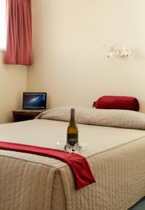 因弗卡吉尔巴伐利亚汽车旅馆 的一间卧室配有两张床和一瓶葡萄酒