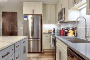 马里兰高地Kasa Forest Park St Louis的厨房配有白色橱柜和不锈钢冰箱