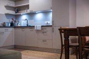 路茨曼贝格Tschardakenhof Appartements的厨房配有白色橱柜、桌子和椅子