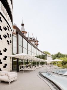 苏黎世The Dolder Grand - City and Spa Resort Zurich的一座带桌子和遮阳伞的建筑和一个游泳池