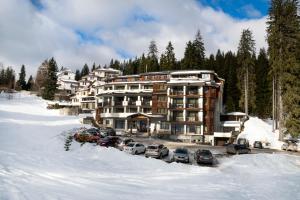 潘波洛沃Hotel Niken的一座大建筑,里面装有汽车停在雪上