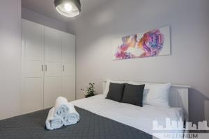 华沙Millennium Awangarda Grey的卧室配有白色的床和墙上的绘画作品