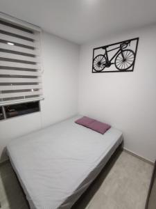 比亚维森西奥Encantador y acogedor apto amoblado villavicencio的卧室配有一张床,墙上挂着自行车