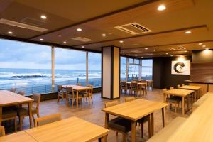 鹤冈市Ikkyu -Seaside Hotel-的一间带桌椅的海景餐厅