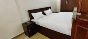 奈尼塔尔Nature Heights BNB的卧室配有一张带白色床单和枕头的大床。
