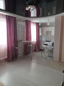 乌里扬诺夫斯克Симбирские апартаменты на Варейкиса 42的厨房配有粉红色的窗帘和桌椅