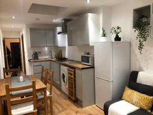 WellingModern apartment in Bexley - 25 minutes from central London的厨房配有白色冰箱、桌子和椅子