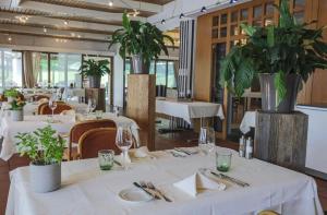 阿尔邦西格腾酒店及餐厅 的一间设有白色桌椅的餐厅,种植了植物