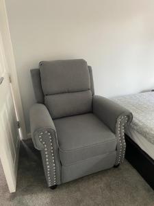 伯明翰Aylesbury Manor的一张灰色椅子,坐在床边