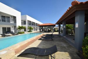 棕榈滩Arena Condos Aruba - few steps from Eagle Beach!的一座带躺椅的游泳池,位于大楼旁