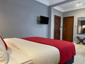 雅温得LA ROCHELLE HOTEL的一间卧室配有一张带红色毯子的大床