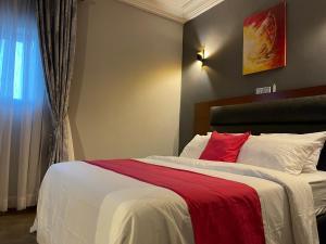 雅温得LA ROCHELLE HOTEL的一间卧室配有一张带红色枕头的大床