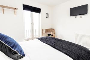 剑桥Cambridge House Hotel的一间卧室配有一张床和一台平面电视