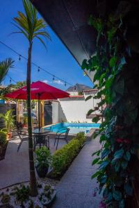 圣佩德罗拉拉古纳El Delfin Hotel y Restaurante的一个带棕榈树和红伞的庭院