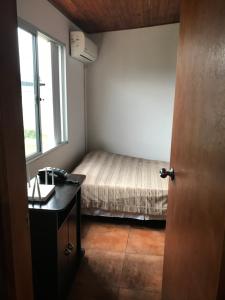 米纳斯Confortable espacio en Minas的一间卧室配有一张床、一张书桌和一个窗户。