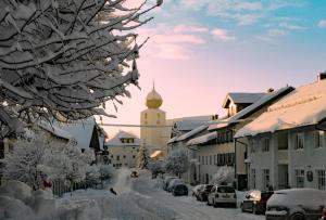 拉姆Bayerische Gastwirtschaft Dimpfl-Stadl的一座被雪覆盖的城镇,有钟楼
