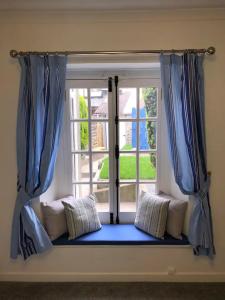 普里茅斯The Retreat @ The Old Smithy, Colebrook Village的窗户前设有蓝色窗帘和枕头