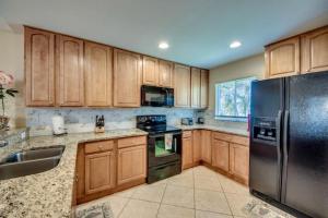 珊瑚角Villa Florida Vacation的厨房配有木制橱柜和不锈钢冰箱。