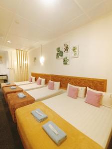昆达桑Bayu Senja Lodge的客房配有4张带粉色和白色枕头的床。