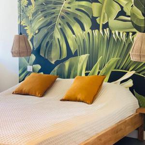Anse Marcel Studio tropical, beautifully renovated, sea view的一张带两个枕头和一幅叶子壁画的床