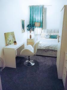 布雷得佛COSY DOUBLE ROOM CLOSE TO UNIVERSITY OF BRADFORD AND CITY CENTRE的卧室配有白色的办公桌和白色的椅子