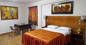 利马热情旅馆的卧室配有1张床、1张桌子和1把椅子