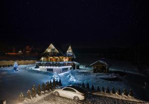 新塔尔格Domek w górach DeLuxe sauna,jacuzzi,basen,hot tub-Nowy Targ blisko Białka ,Zakopane的雪中停在房子前面的汽车