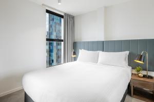 墨尔本Brady Apartment Hotel Hardware Lane的卧室设有一张白色大床和一扇窗户。