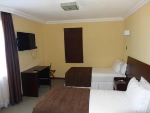 安托法加斯塔Hotel Costa Pacifico - Express的酒店客房设有两张床、一张桌子和一台电视。