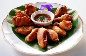 Ban Cham Khaจำค่า ชาเลท์ บ้านพักสวนเกษตร (Jumka Chalet - Home and Farm Stay)的配鸡翅和 ⁇ 酱的盘子