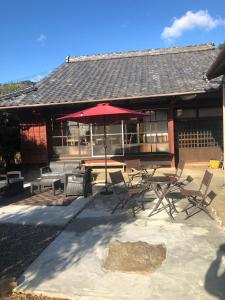 田边市Kumano Winery Guest House的庭院配有桌椅和遮阳伞。