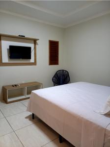 圣米格尔-杜戈斯托苏Pousada Império的卧室配有一张床,墙上配有电视。
