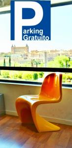 托莱多TOLETUM low cost LOFTS diáfanos o 2dormitorios PARKING Municipal Gratis al aire libre a 100m的坐在窗前的橙色椅子