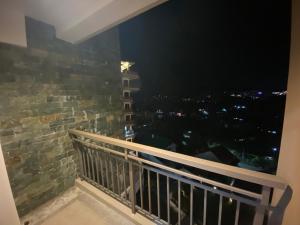 碧瑶Rosarich Homestay - Bristle Ridge Residences的阳台,晚上可欣赏到城市景观