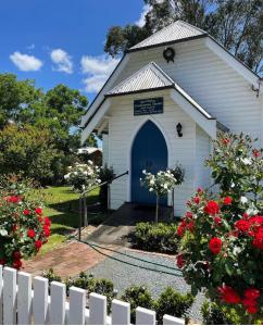 巴灵顿The Church at Barrington的白色的教堂,有蓝色的门和红色的鲜花
