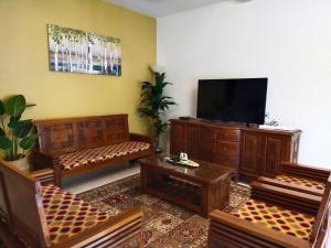 斯里伊斯兰德Kayu Cengal Homestay的客厅配有木制家具和平面电视