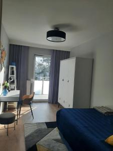 奥莱茨科Luksusowy Apartament Parkowa Olecko的一间卧室配有蓝色的床、一张书桌和一个窗户。