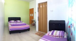 怡保怡保TZY民宿的紫色和紫色床单的客房内的两张床