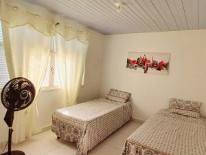 纳塔尔Casa Petit - Banheiro Exclusivo的一间卧室设有两张床和窗户。