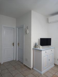 圣特奥多罗Appartamento Piano Terra Residence Geranium Beach的一间白色的房间,在柜台和门上配有电视