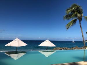 苏莎亚Vacations in the Caribbean Paradise的一个带两把遮阳伞的游泳池以及大海